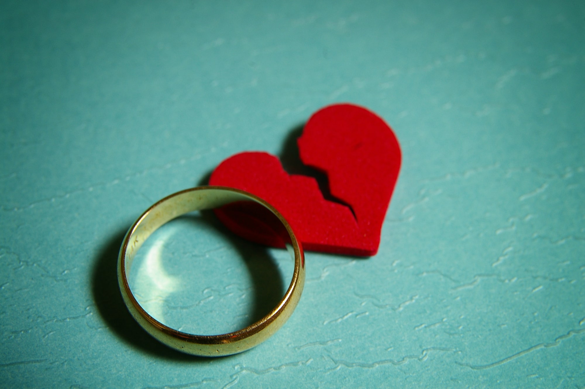 Spousal Maintenance in Texas: Understanding the Basics and Implications - wedding ring, broken red heart, on blue paper background